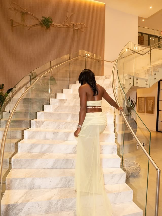 Alycia Parks from behind walking up the marble staircase, the gown train following the steps